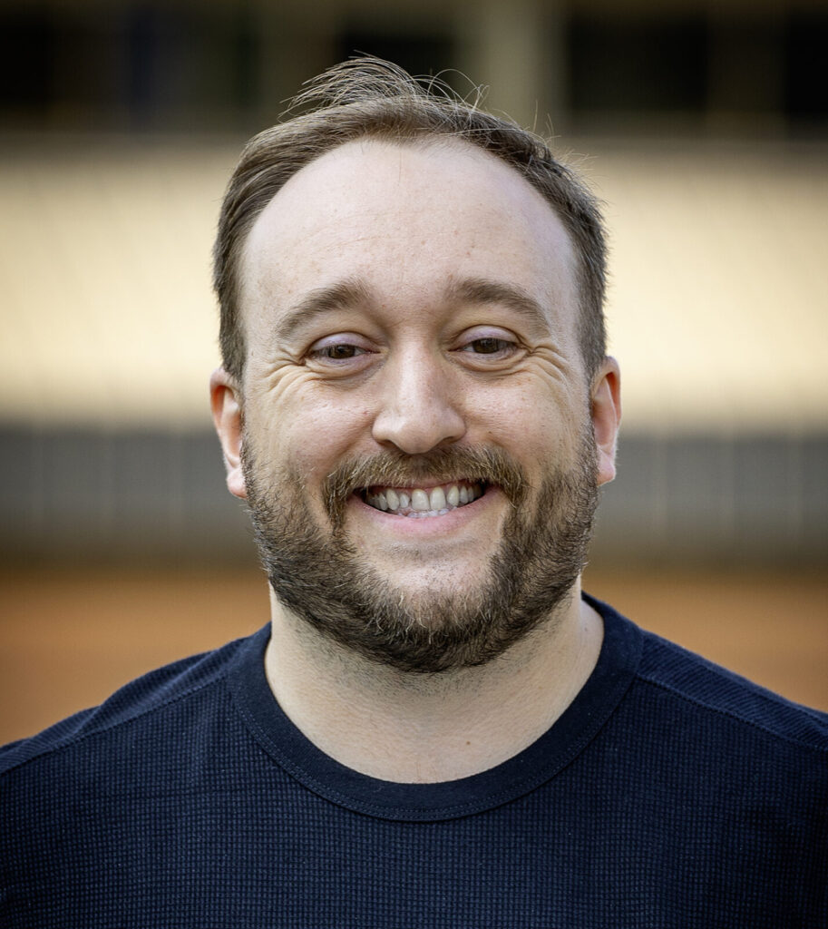 A man in a black t-shirt against a beige and brown background