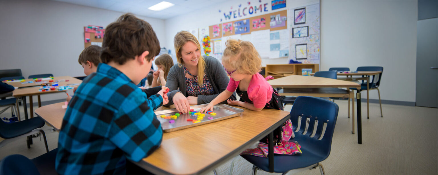 A woman teaching a child the ABC in a classroom setting