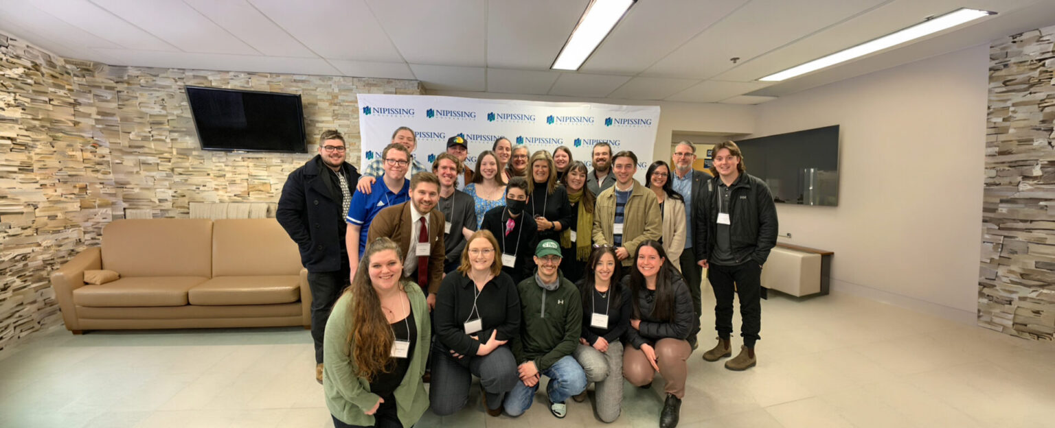 A group of history students with the history professor standing together in the cafeteria