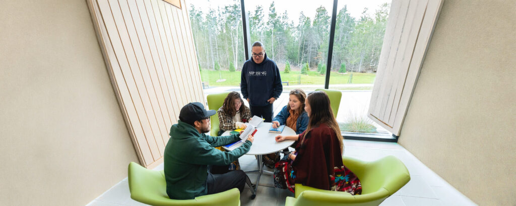 A group of students studying at a white table in the student centre