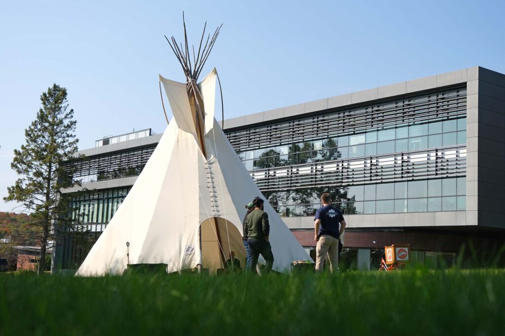 The tipi outside the library with people standing around it