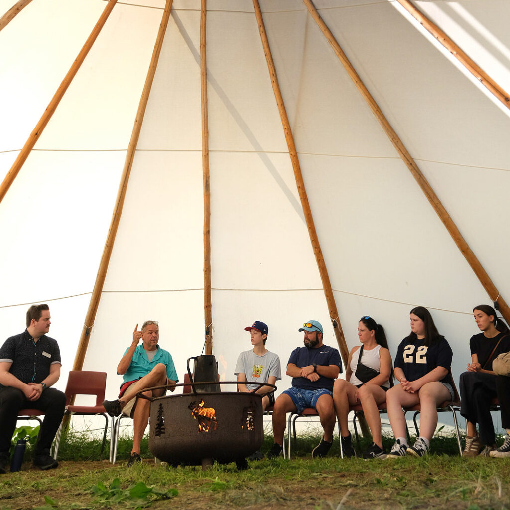 A group of people sitting inside the tipi