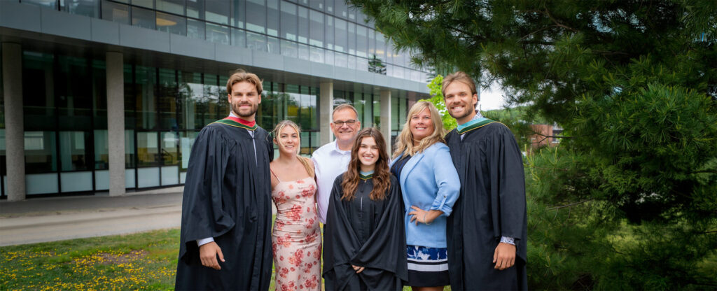 A group of graduates in gowns and their family taking picture in front of the library