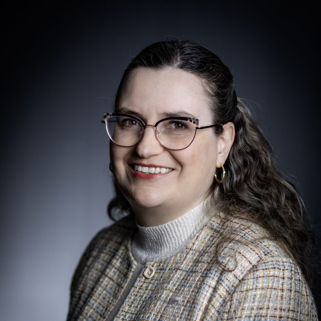 A professor in tweed shirt against a well-lit dark background
