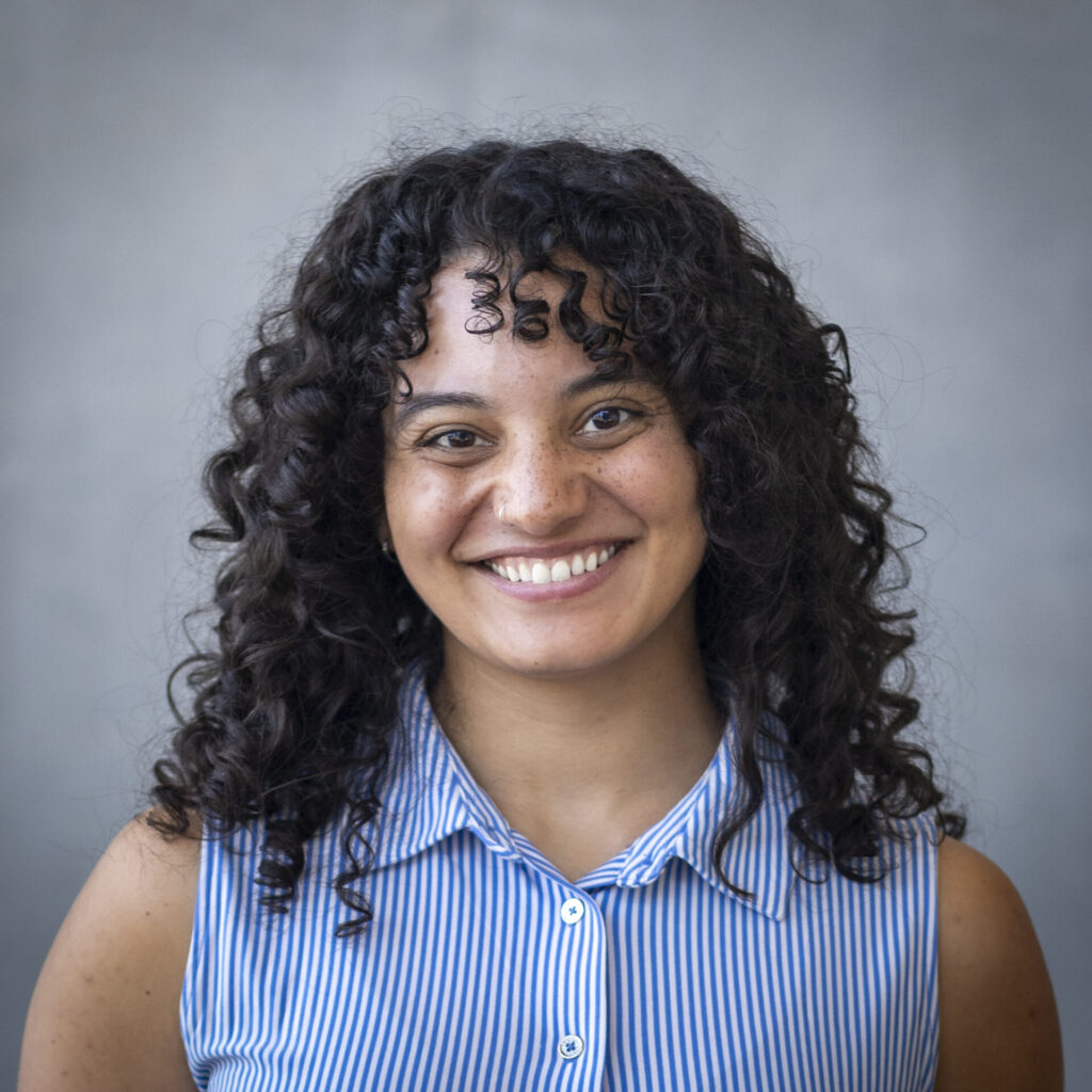 A woman in blue and white striped shirt against a grey background