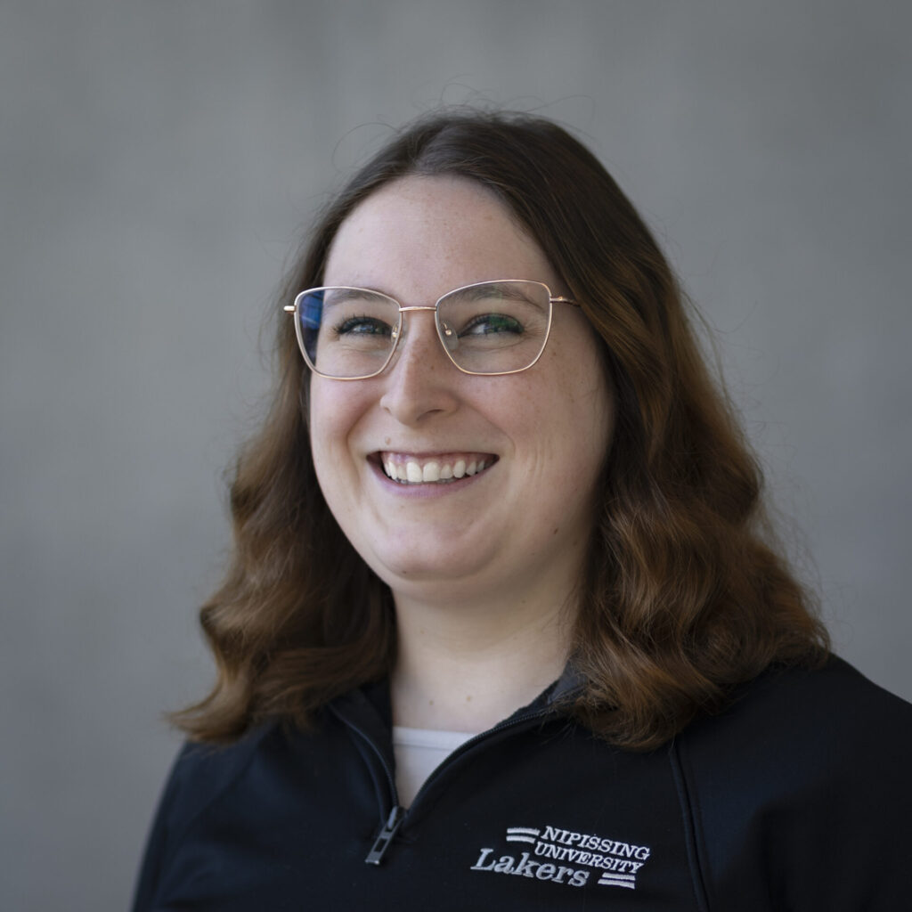 A woman in navy Nipissing zip up against a grey background